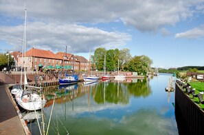 A canal with boats docked, a brick building, and a clear sky.
