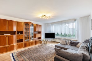 Un salon avec un canapé, un téléviseur, des meubles en bois et un tapis à motifs.