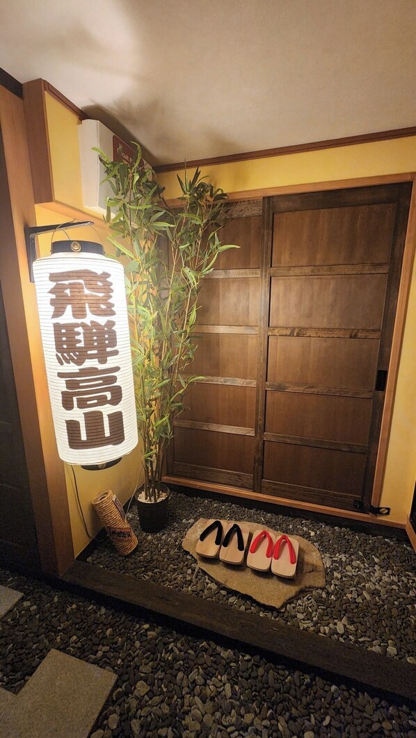 Una habitación japonesa tradicional con suelo de tatami, una planta de bambú y una puerta corredera de madera.
