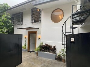 Una casa moderna con escalera, puerta y jardín con plantas.
