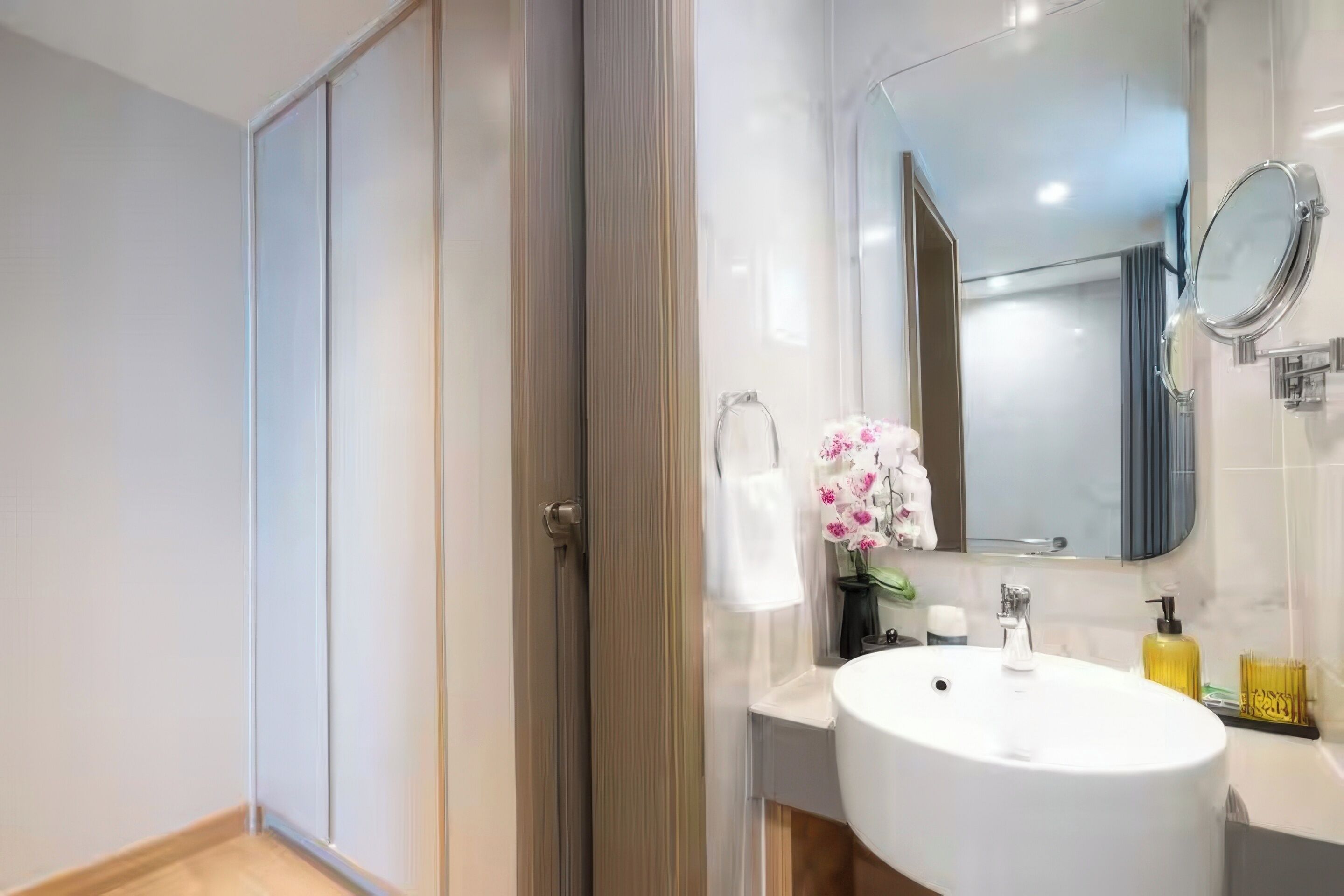 A modern bathroom with a white sink, mirror, and a glass shower enclosure.