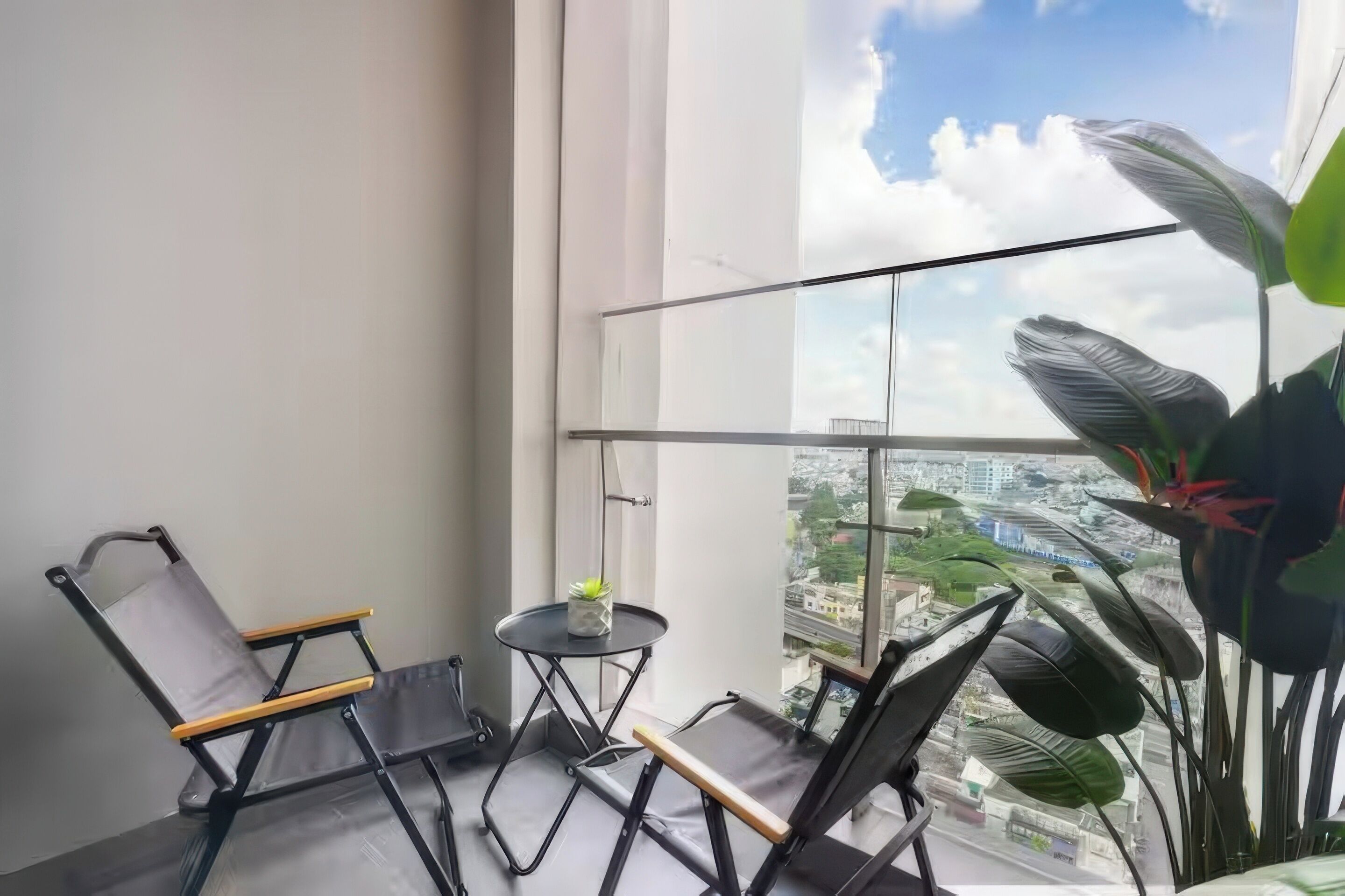 Un balcon avec deux chaises, une petite table et un pot de fleurs.