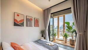 A modern bedroom with a large bed, a city view through a sliding door, and three abstract wall art pieces. - Imperial Elegance Zenity D1 (Ho Chi Minh City)