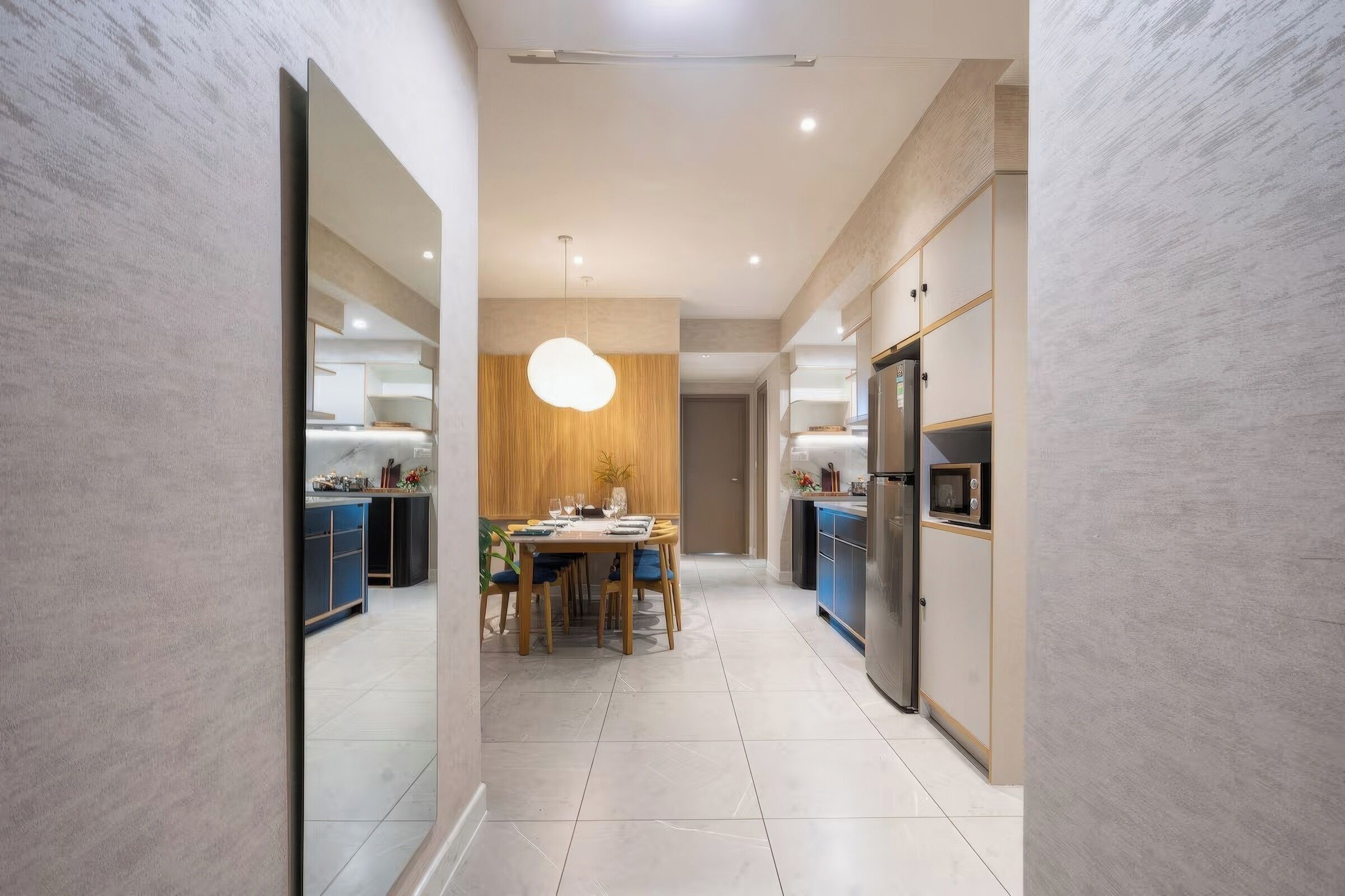 Una cucina moderna con zona pranzo, caratterizzata da una grande isola, elettrodomestici contemporanei e una lampada a sospensione.