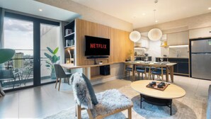 A modern living room with a large flat-screen TV, a dining area, and a kitchen. - Imperial Elegance Zenity D1 (Ho Chi Minh City)