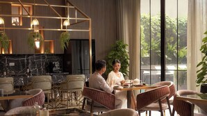 A modern dining area with a marble countertop, wicker chairs, and hanging plants. - Imperial Elegance Zenity D1 (Ho Chi Minh City)