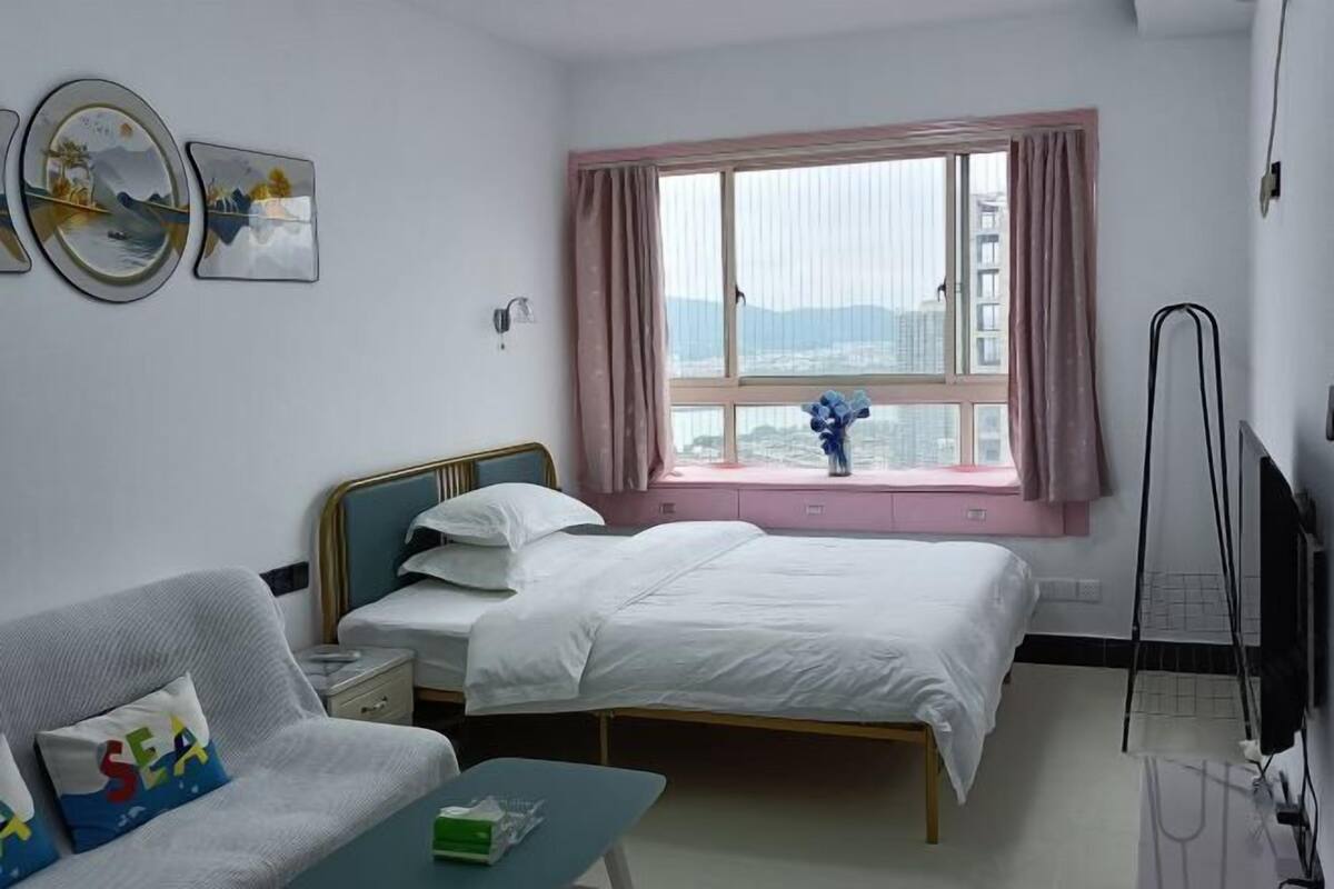 Een hotelkamer met twee bedden, een sofa, een raam met gordijnen, een flatscreen televisie en kunstwerken aan de muur.