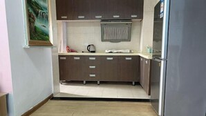 Cozinha com armários de madeira, geladeira de aço inoxidável e painel de azulejos.