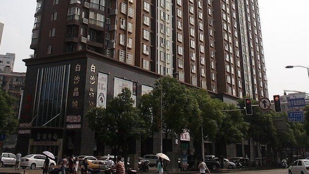 Um edifício residencial alto com várias varandas e área comercial no térreo com sinalização.