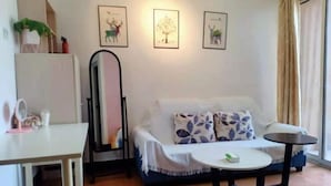 Uma sala de estar com sofá, mesinha, espelho e quadros na parede.