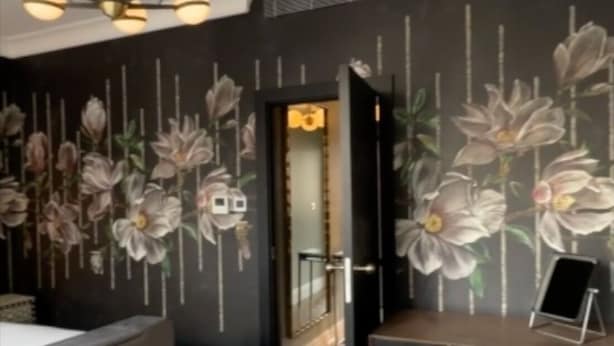 Een moderne kamer met een bureau, stoel en een decoratieve wand met bloemenmotieven.