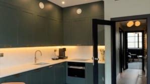 Een moderne keuken met donkere kastjes, een houten eettafel en een inbouwoven.