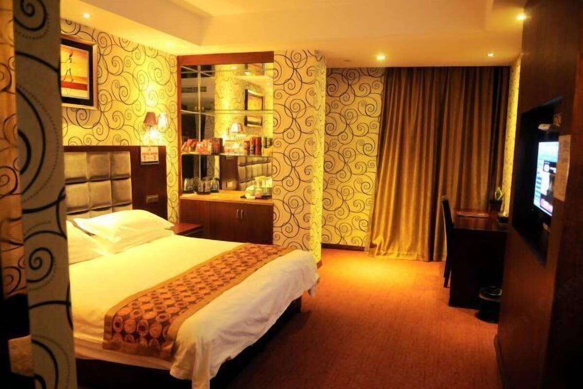 A hotel room with a bed, a desk, a television, and a minibar.