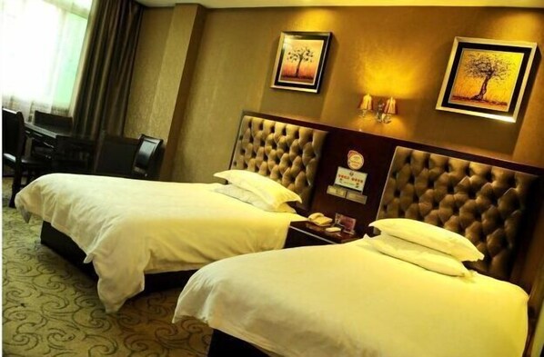 A hotel room with two beds, a desk, and a chair. There are framed pictures on the wall and a clock on the nightstand. - Haoting Motel (Pingyang)