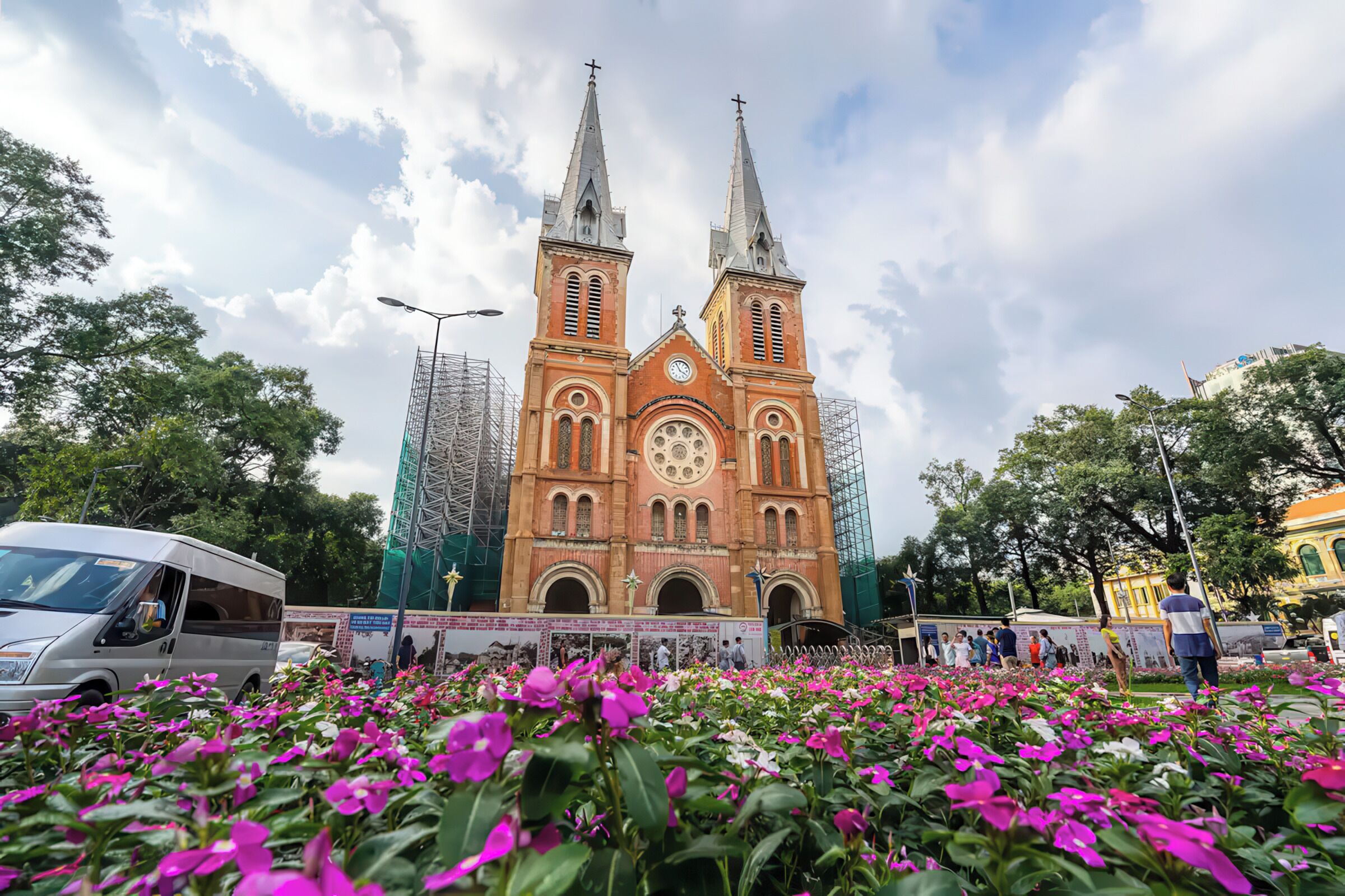 A large church with two towers and a clock in the center, surrounded by a field of pink flowers.