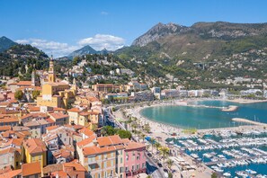 A coastal town with a marina, a church, and a mountain backdrop.