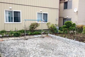 A residential building with a gravel courtyard, a small garden with various plants, and a metal structure in the center. - spacious room close to JR station Free WIFI parking lot (Ebetsu)