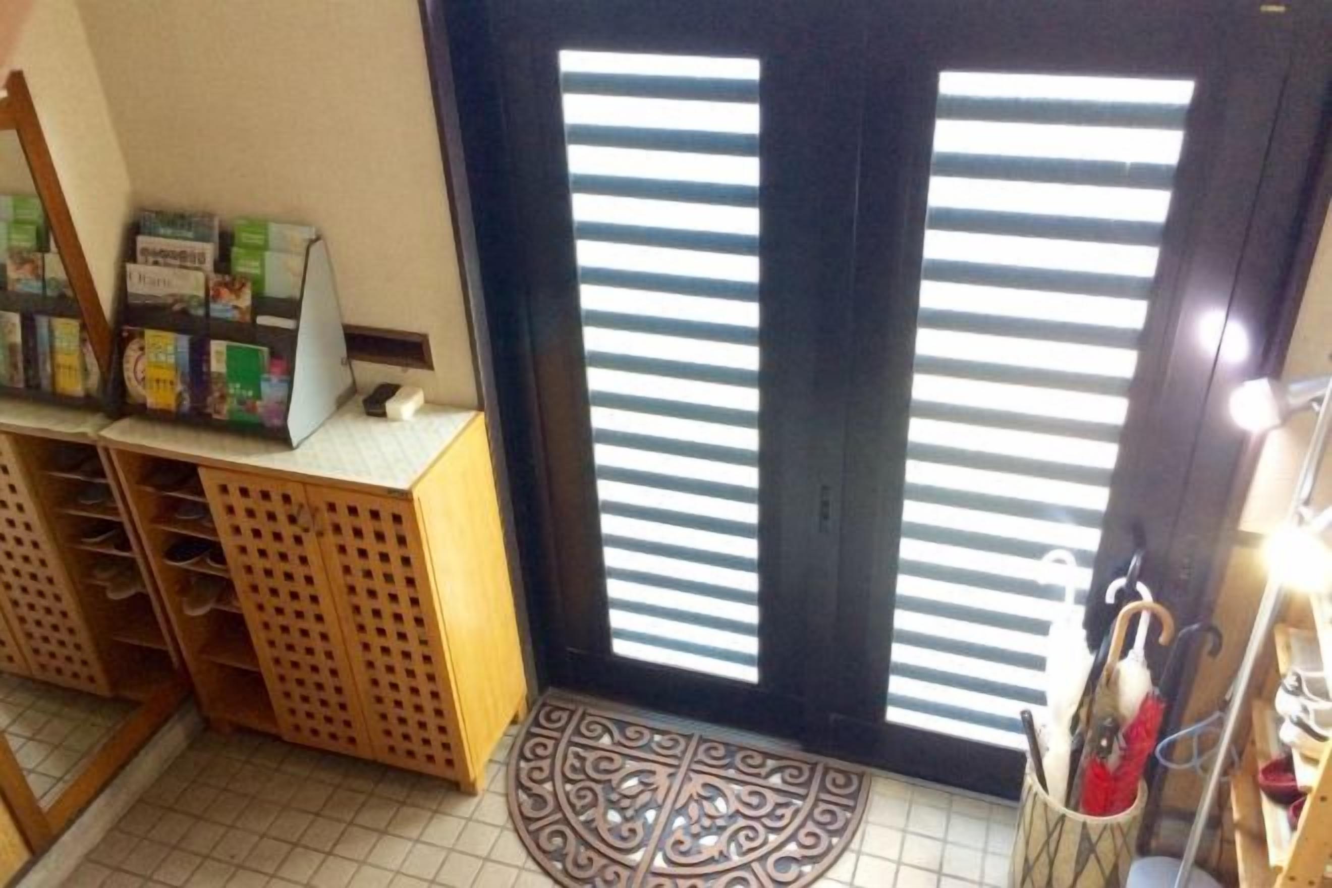 Una habitación con una puerta, un estante con objetos y un tapete estampado.