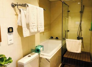 Une salle de bain équipée d’une baignoire, d’une douche à parois de verre, de toilettes et d’un porte-serviettes avec plusieurs serviettes.