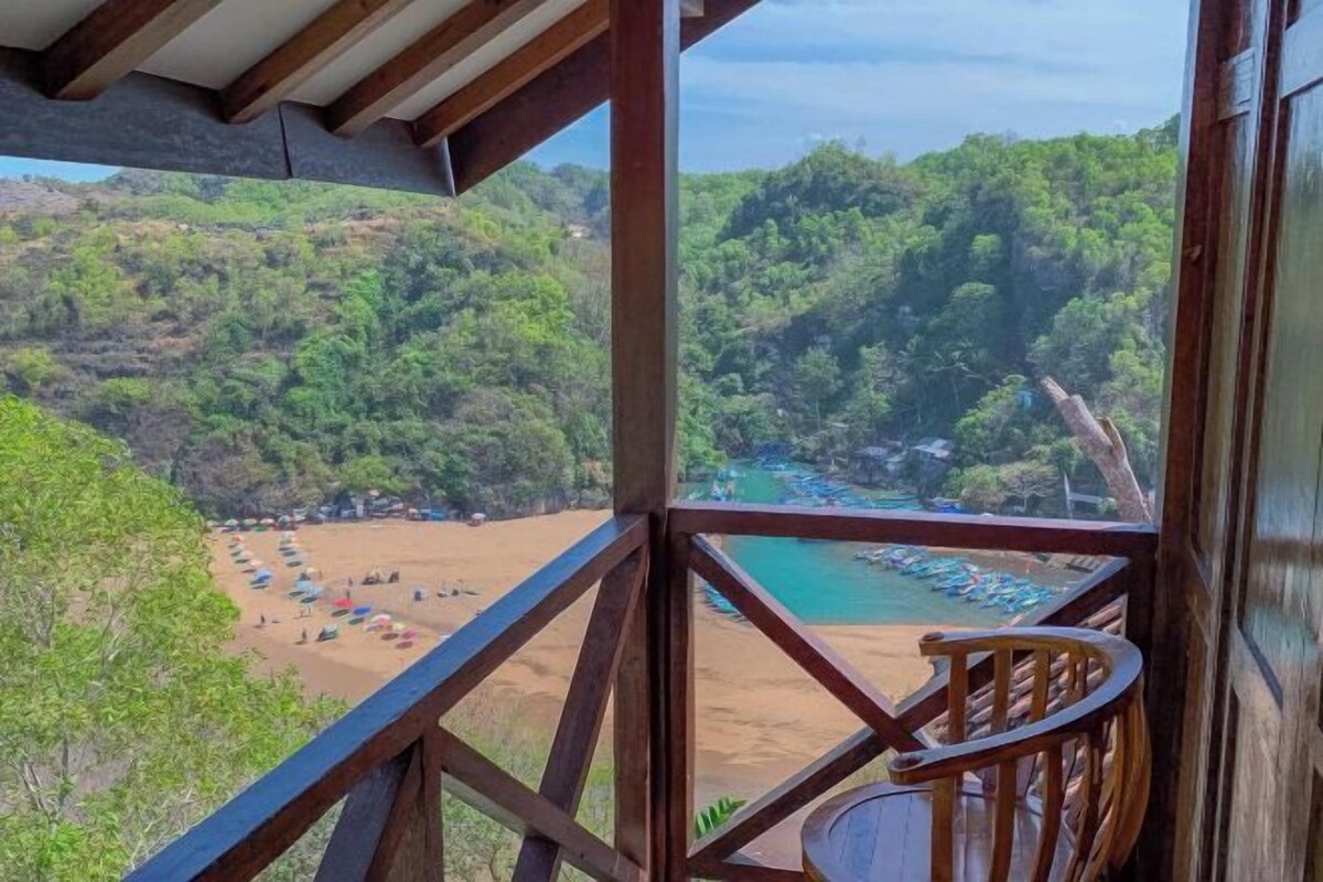 Varanda com vista para uma praia e área arborizada.
