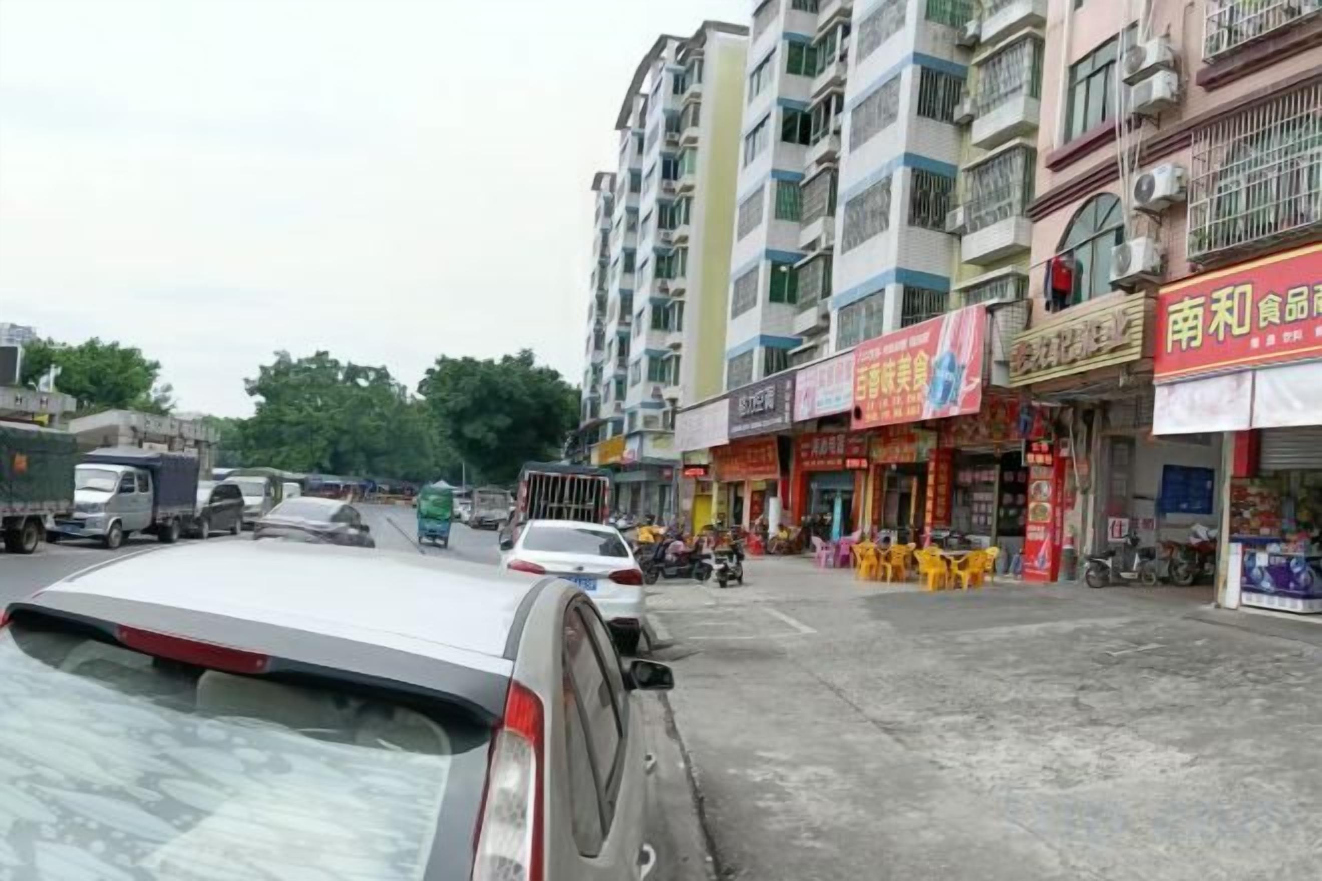 Eine Straße mit Gebäuden, Geschäften und geparkten Fahrzeugen.