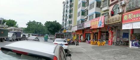A street with buildings, shops, and parked vehicles.