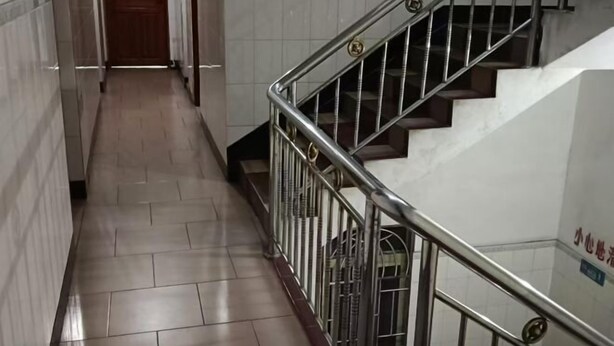 A hallway with tiled flooring and a metal railing leading to a staircase. - Huaiji Tianyuan Travel Industry (Huaiji)