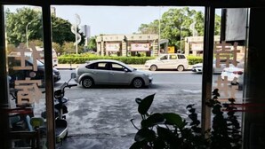 A view through a glass door of a building with a parked car and a scooter inside. - Huaiji Tianyuan Travel Industry (Huaiji)