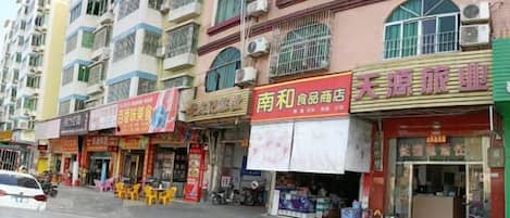 Un edificio de varios pisos con diferentes comercios en la planta baja, incluyendo un restaurante y una tienda de conveniencia.