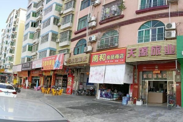 Un edificio de varios pisos con diferentes comercios en la planta baja, incluyendo un restaurante y una tienda de conveniencia.