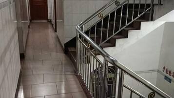 A corridor with a metal railing and a staircase with a wooden door at the end.