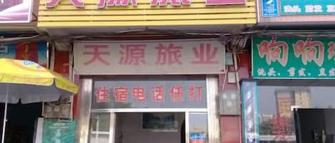 Fachada de un local con un letrero que dice '天源旅游业' y un aviso de servicio de reservas telefónicas para alojamiento.