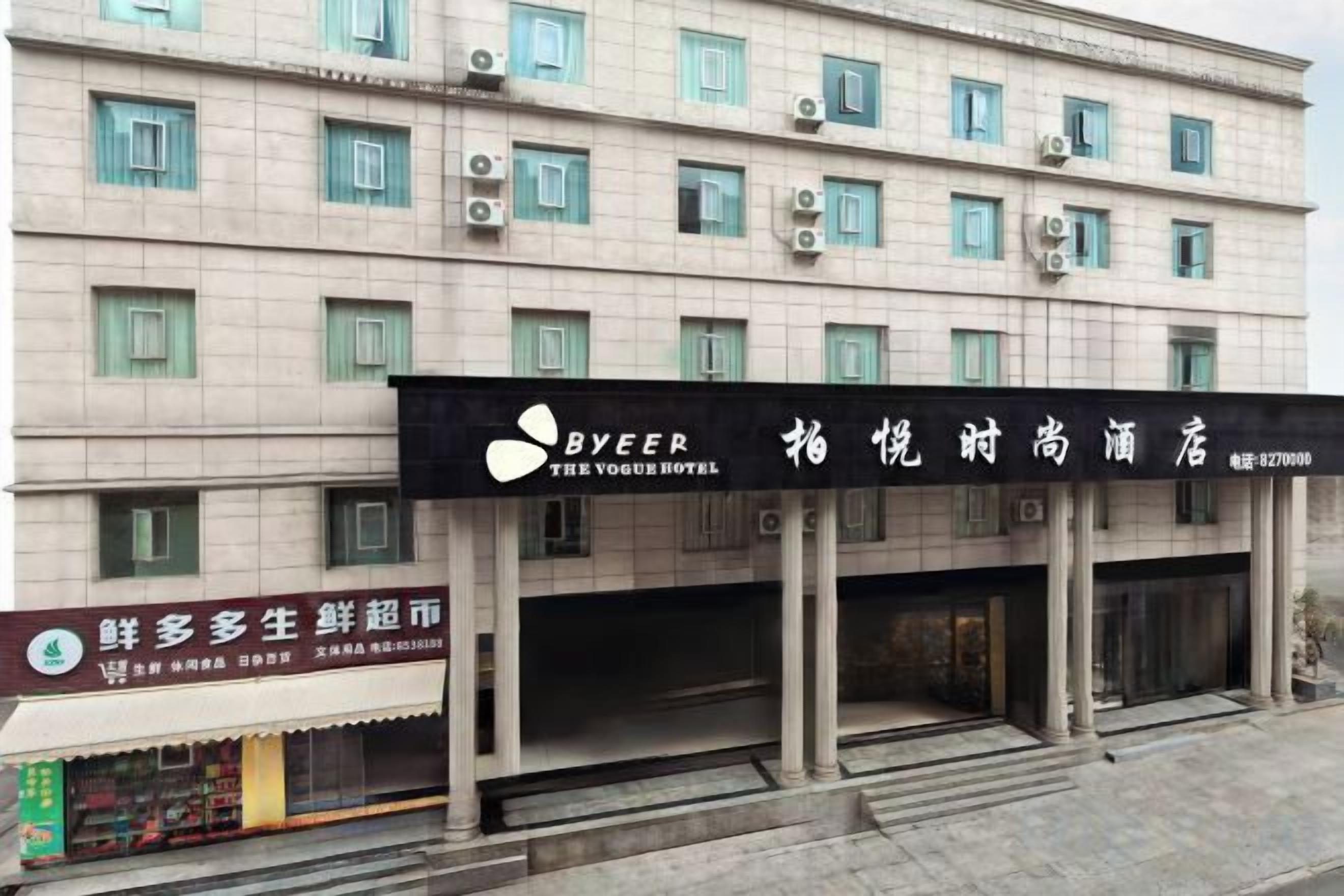 Un hôtel à plusieurs étages, une enseigne bien visible indiquant « BYEER THE VOGUE HOTEL », et une devanture avec une enseigne pour un restaurant de fruits de mer.