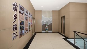 A hallway with a tiled floor, a wall with text, a vase, and a door. - Park Hyatt Fashion Hotel (Kaili cross street people's hospital) (Kaili)