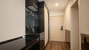 A narrow hallway with a kitchen area on one side, a door at the end, and a wooden floor. - Park Hyatt Fashion Hotel (Kaili cross street people's hospital) (Kaili)
