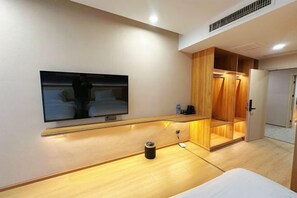 A modern hotel room with a flat-screen TV mounted on the wall, a wooden vanity, a bed, and a walk-in closet. - Park Hyatt Fashion Hotel (Kaili cross street people's hospital） (Kaili)