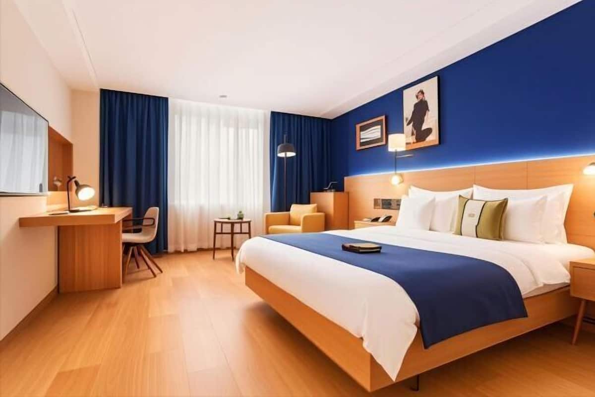 Ein Hotelzimmer mit einem großen Bett, einem Schreibtisch, einem Stuhl und einem kleinen Tisch.