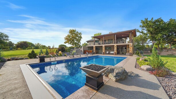 Una moderna casa a due piani con piscina, area salotto esterna e un giardino curato.