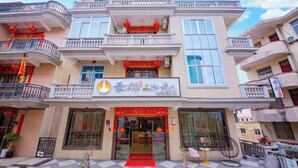 Un immeuble à plusieurs étages dont la façade comprend un magasin avec un auvent rouge et une enseigne portant des caractères chinois.
