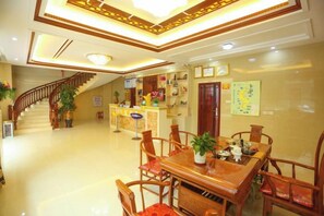 A hotel lobby with a reception desk, a staircase, and a dining area with wooden furniture. - Weizhou Island Jingdu Hotel (Mazu Zumiao Branch) (Putian)