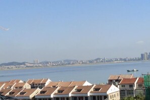 A coastal cityscape with a row of terraced houses and a body of water in the background.