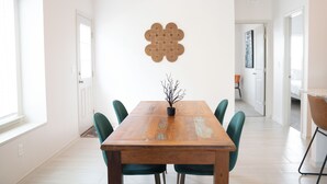 Ein Essbereich mit Holztisch, vier Stühlen, einer Chandelierleuchtre und einer Wanddekoration.