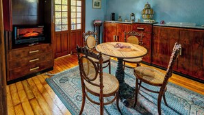 Een eetgedeelte met een houten tafel, vier stoelen, een open haard en houten kasten.