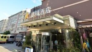 Un hotel con fachada moderna, un acceso cubierto y una señalización con caracteres chinos visible.