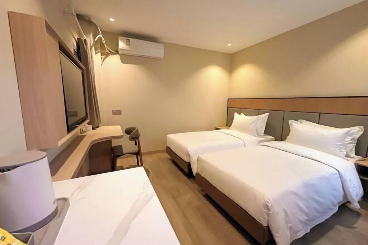 Een hotelkamer met twee bedden, een bureau, een stoel en een televisie.