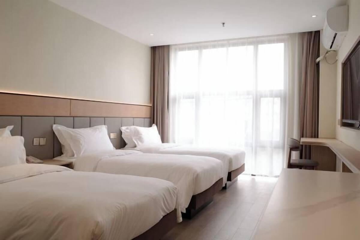 Een hotelkamer met twee bedden, een bureau en een groot raam.