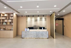 A reception area with a marble counter, wooden shelving, and a curtain divider. - Joyful Star Hotel (Shanghai)
