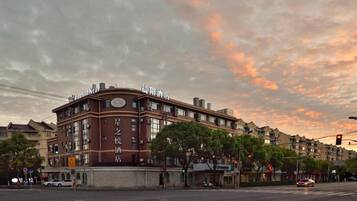A hotel with a prominent sign, multiple floors, and a street view with cars and traffic lights.