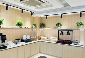 A modern kitchen with wooden cabinets, a coffee machine, and potted plants. - Joyful Star Hotel (Shanghai)
