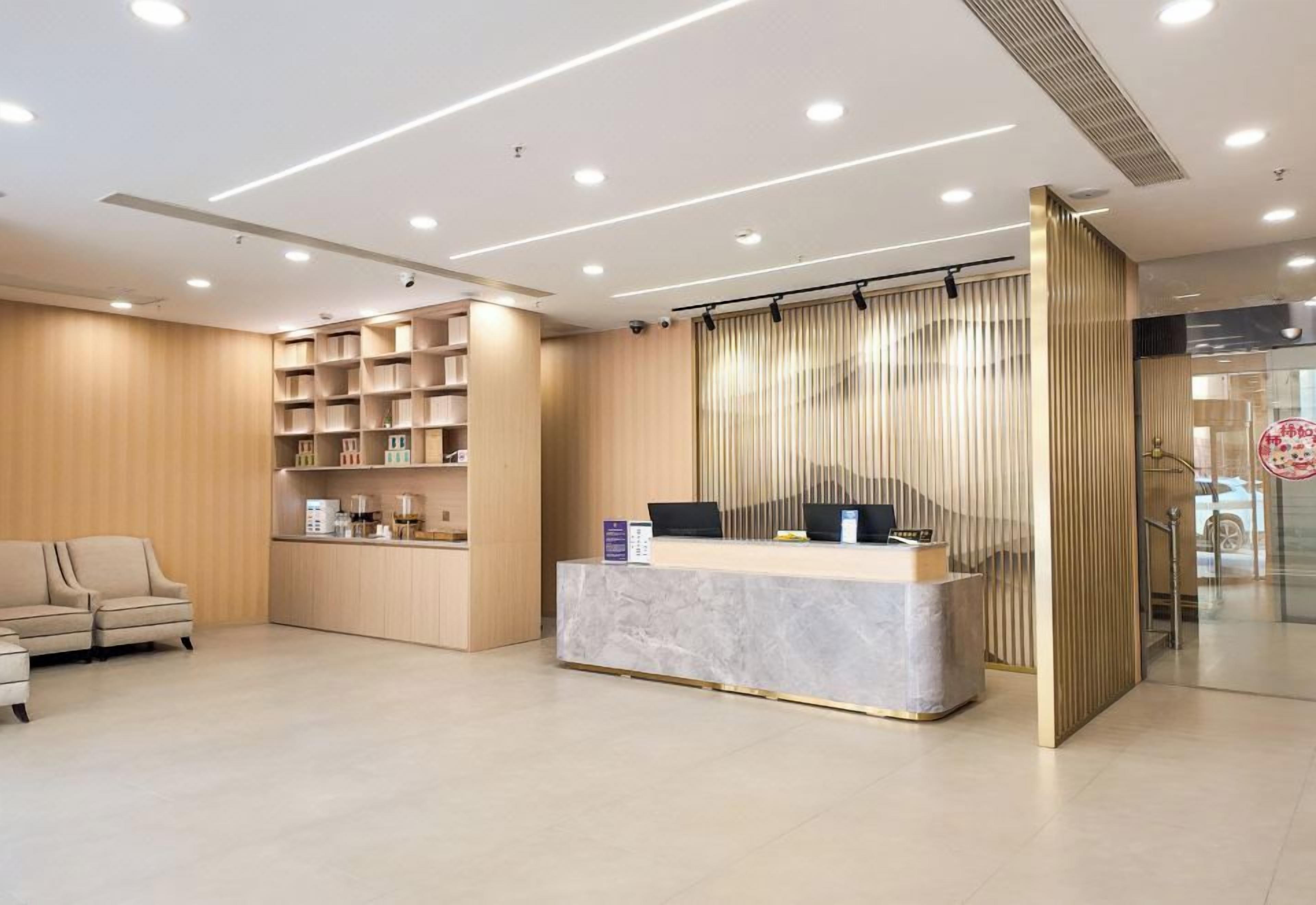 A modern reception area with a marble counter, a sofa, and a wooden shelving unit.
